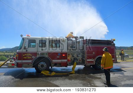 KALISPELL, MONTANA, USA - June 21, 2017: Firefighter sprays water onto a grass fire from the top of a fire truck