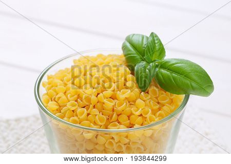 glass of small pasta shells on white table mat - close up