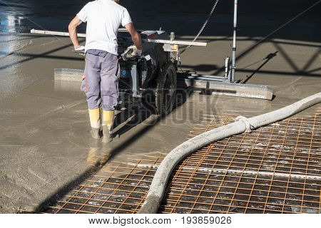 Construction worker with concrete floor laser leveling screed machine