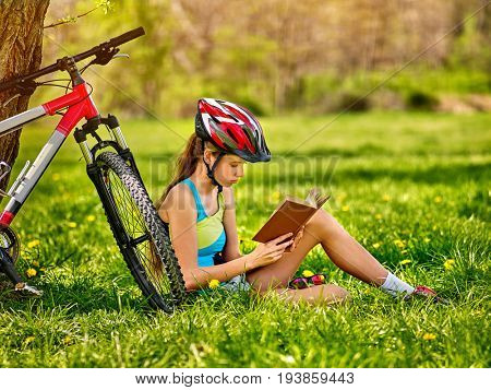Woman traveling bicycle in summer park. Girl read book on rest near your vehicle. Cycling is good for health. Cyclist is preparing for exam in park. Reading and sport in summer vacation.