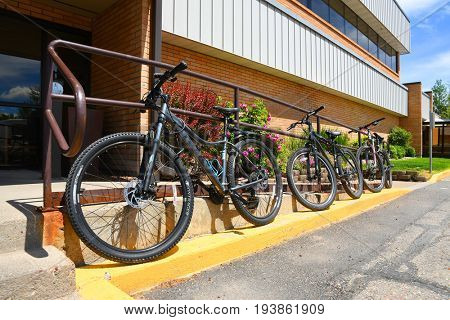 KALISPELL, MONTANA, USA - June 21, 2017: Row of mountain bikes locked onto railing outside an office building
