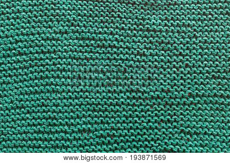 A close-up of a green knitted sweater. Patterns texture