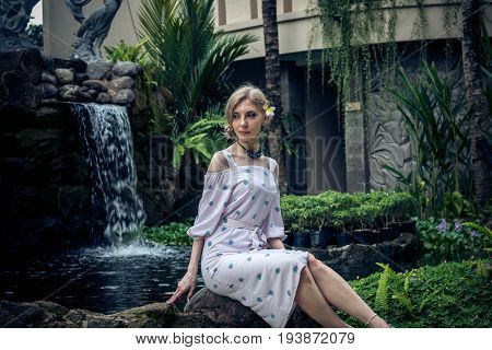 Woman is posing in a tropical garden of Bali island.