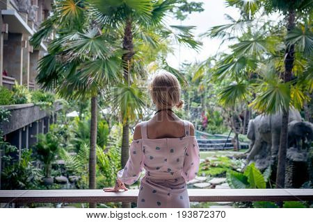 Woman is posing in a tropical garden of Bali island.