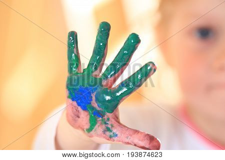 Kid hand in green paint close-up. Dirty child hand after drawing lessons.