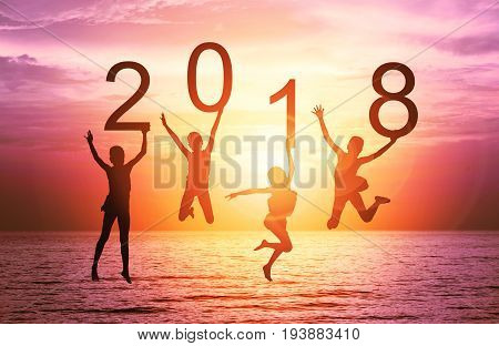 Happy new year card 2018. Silhouette of children girl is jumping on tropical beach with fantastic sunset sky background. Kids holding the number 2018 with sea and sunrise background.
