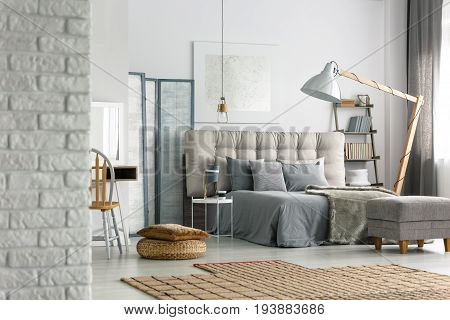 Cozy grey bedroom in modern loft with white brick wall