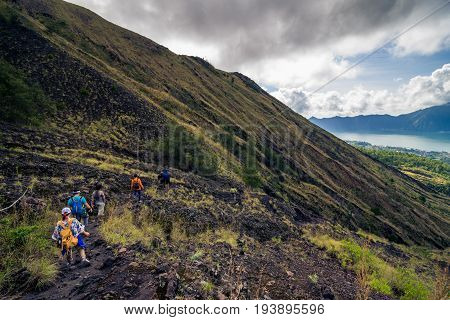 Group of hikers descending on friable ground in the caldera of volcano of Batur. Bali, Indonesia