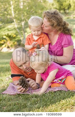 Ung familie taler om kogler i parken på en sommerdag.