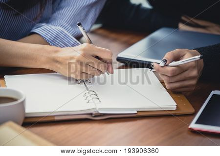 Closeup woman hand holding pen for writing on the book woman working concept