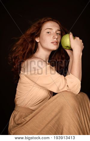 sensual redhead woman posing with green apple isolated on black