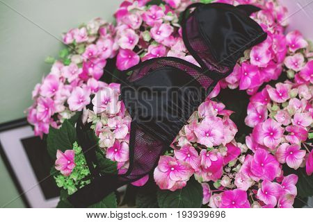 Female black lace bra on aflowers background. Handmade lace bra