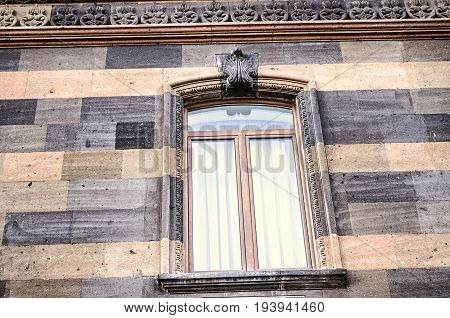 Carved stone pattern on the cornice and arched window frame with the stylized sheet ornament in the centre