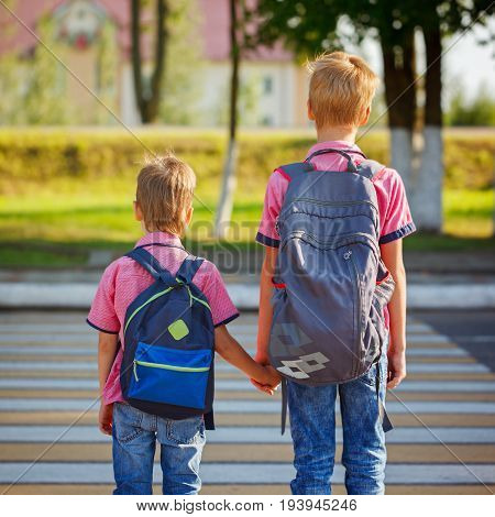 Two Kids With Backpacks Walking On The Road, Holding. School Time