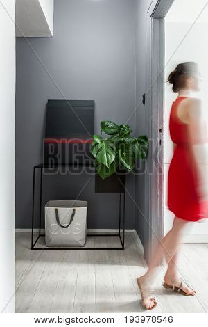 Woman wearing red dress standing in modern apartment with decorative painting