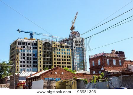 SAMARA, RUSSIA - JUNE 21, 2017: A house under construction and construction cranes on background of blue sky. Construction is conducted on Krasnoarmeyskaya Street.