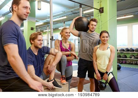 fitness, sport, exercising and healthy lifestyle concept - group of happy people with skipping rope, medicine ball and kettlebell in gym