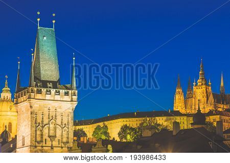 Prague Castle in Mala Strana district and Charles Bridge Tower during blue hour sunset in Czech Republic.
