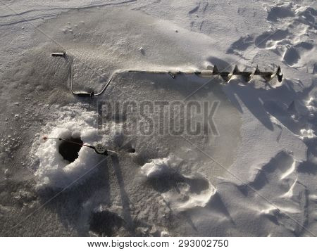 Ice Fishing In The Strong Wind. Fishing Rod, Ice-drill, Wind Carries Snow (drifting Snow), Icing