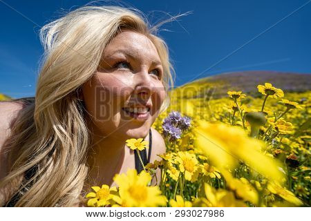 Beautiful Blond Woman In A Yellow Wildflower Field, Looking Up At A Blue Sky In Spring. Taken At Car