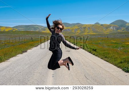 Woman Jumping In The Middle Of The Empty Road In Carrizo Plain National Monument During The Californ