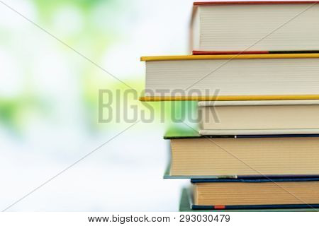 Multikolor Book Stack In The Library Room On Tabel And Blurred Trees On Street Back To School Concep