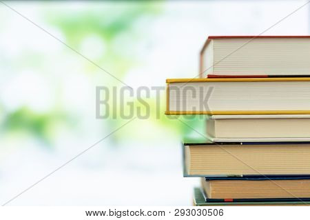 Multikolor Book Stack In The Library Room On Tabel And Blurred Trees On Street Back To School Concep