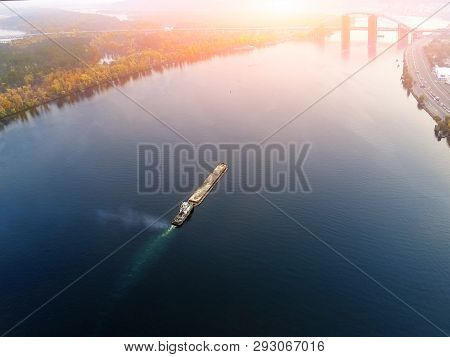 Scenic Aerial Cityscape Of Kiev And River Dnipro At Sunset. Tugboat Supporting Barge With Sand Bulk 