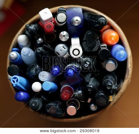 Multi-colored pens in wood cup on wooden table background - view above