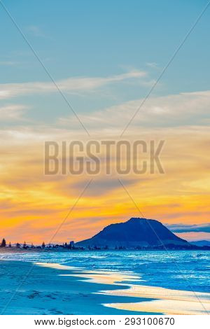 Long Beach Scene With Landmark Mount Maunganui In Distancewith Bright Sunset Colors.