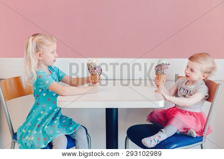 Lifestyle Portrait Of Two Happy Caucasian Cute Adorable Funny Children Girls Sitting Together Braggi