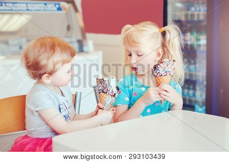 Lifestyle Portrait Of Two Happy Caucasian Cute Adorable Funny Children Girls Sitting Together Sharin