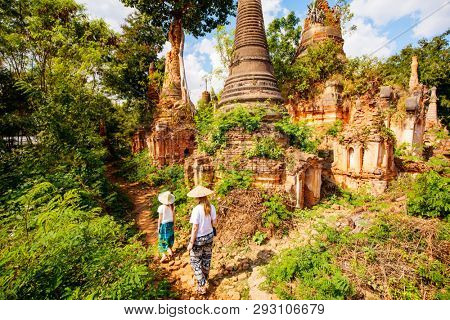 Back view of family mother and daughter visiting hundrets of centuries old stupas in Indein near lake Inle in Myanmar