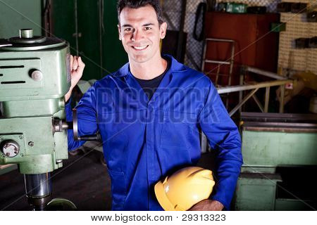 Ritratto di felice industriale artigiano accanto alla macchina utensile
