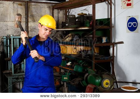 operaio collare blu con grande martello nell'officina