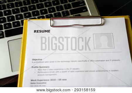 Resume On A Clipboard With Office Table Background. A Hiring Or Employment Concept