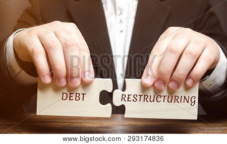 Businessman Collects Wooden Blocks With The Word Debt Restructuring. Debts Relief. Changing Loan Rep