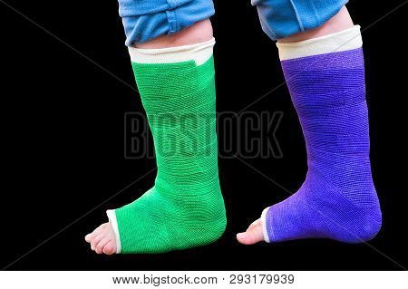 Teenage Boy Walks With Two Colorful Gypsum Legs Isolated On Black Background