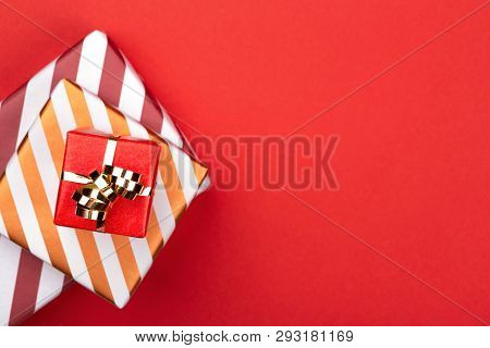 Top View Of Gift Boxes Wrapped In Red And Striped Paper With Golden Bow On Red Background. Christmas