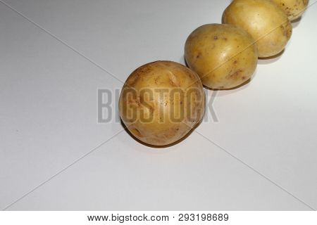 Three Potatoes Lie On A White Background In A Row