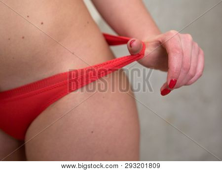 Elegant Female Hand With A Red Manicure Pulls Aside The Elastic Of The Panties On The Thigh. Lingeri