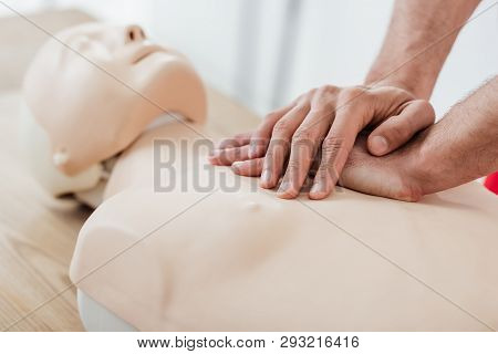 Cropped View Of Man Using Chest Compression Technique On Dummy During Cpr Training