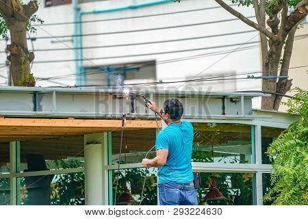 Asian Worker Welds The Steel Stick To Create A Structure For Roof Water Drain., Home Improvements An