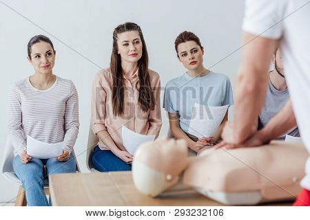 Instructor Performing Chest Compression On Dummy During Cpr Training Class With Group Of People