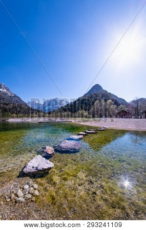 Rocks In Lake Jasna With Mountains Razor And Prisojnik On The Horizont In Slovenia