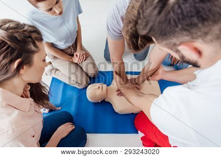 High Angle View Of Instructor Performing Cpr On Dummy During First Aid Training With Group Of People