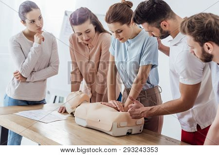 Group Of Focused People Performing Cpr On Dummy During First Aid Training