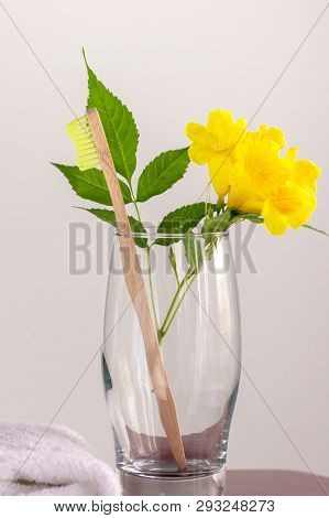 Zero-waste, Biodegradable Bamboo Toothbrush In A Glass With With A Yellow Flower And A White Towel N