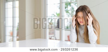 Wide angle picture of beautiful young girl kid wearing casual sweater with hand on head for pain in head because stress. Suffering migraine.