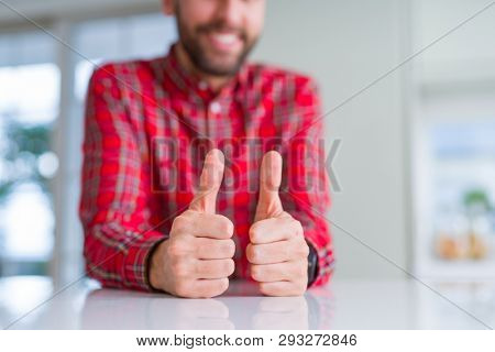Close up of hands man doing thumbs up gesture over white table
